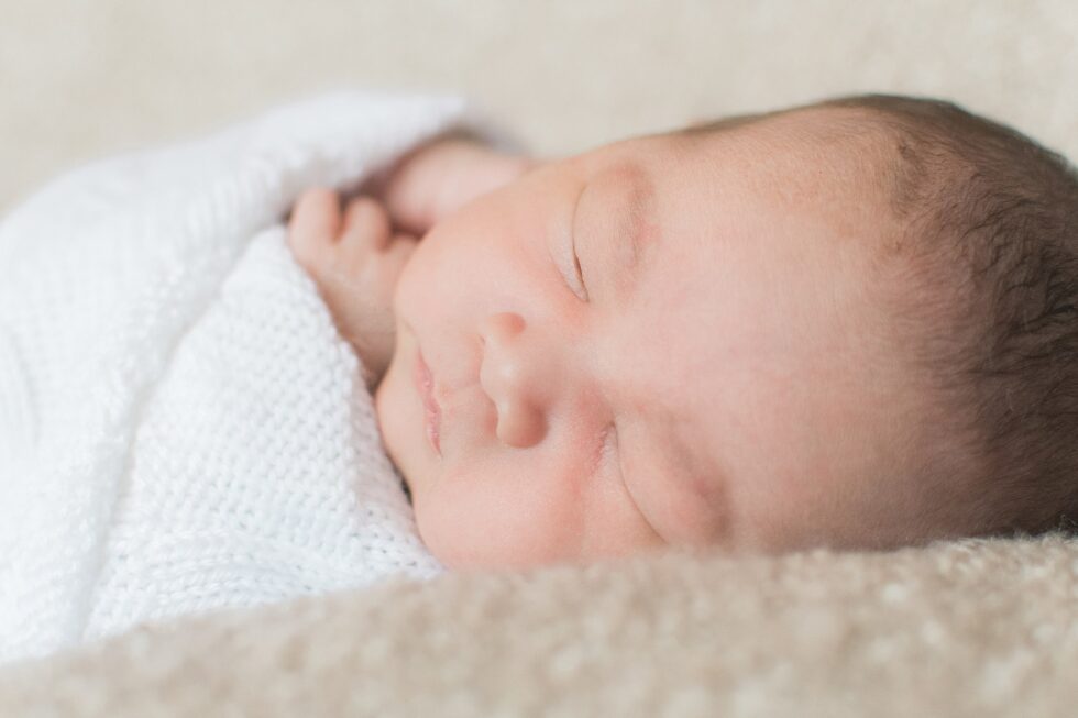 Close-up of a sleeping newborn baby wrapped in a soft blanket during an at-home newborn photography session in Leeds, Yorkshire