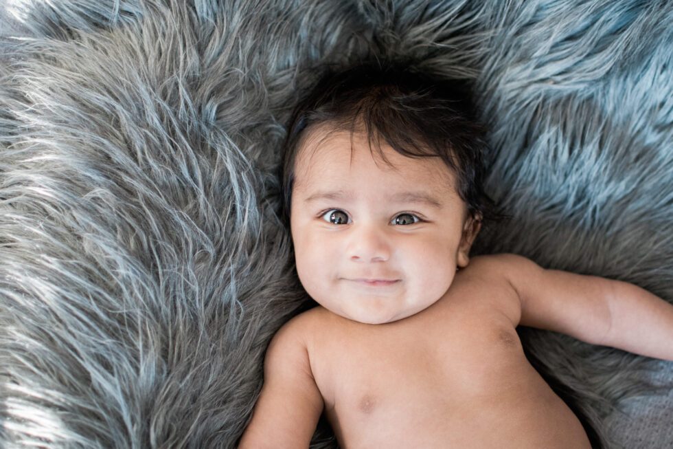 Smiling newborn baby lying on a soft blanket during a relaxed at-home newborn photography session in Settle, Yorkshire Dales