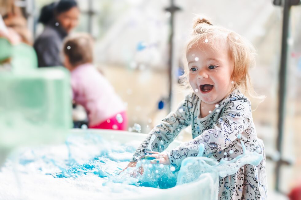 Child playing with water in an outdoor activity during a pre-school photography session for nursery marketing in Leeds, West Yorkshire
