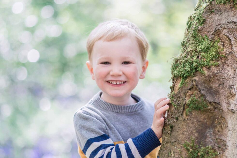 Young boy smiling while playing outdoors during a natural family photo shoot in Ilkley, West Yorkshire