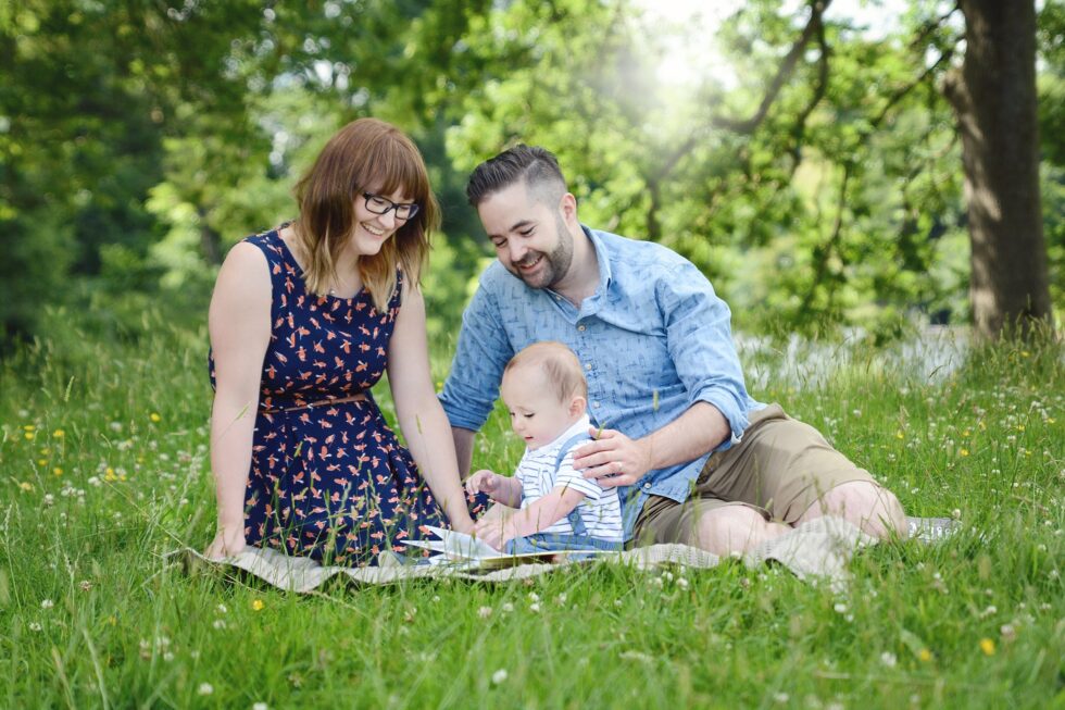 Parents sitting with their baby on a blanket in the grass during a family photography session in Bradford, Yorkshire
