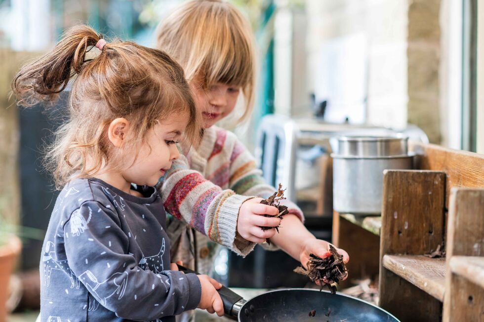 nursery school pupils playing a outdoor mud kitchen, cooking with leaves, in Skipton, yorkshire