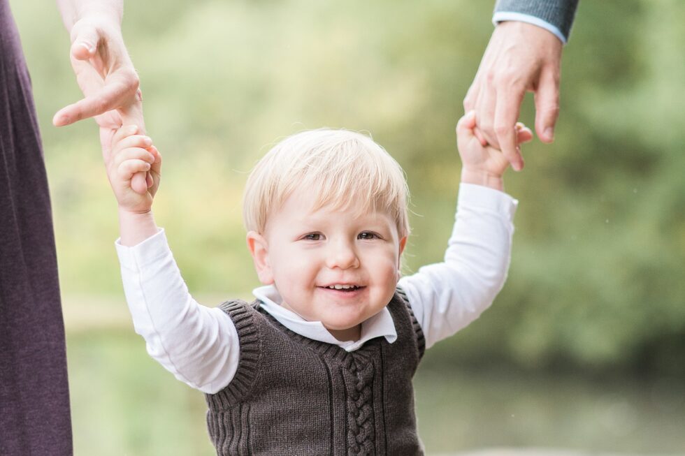 Toddler holding parents' hands during an outdoor family portrait session in Halifax, North Yorkshire