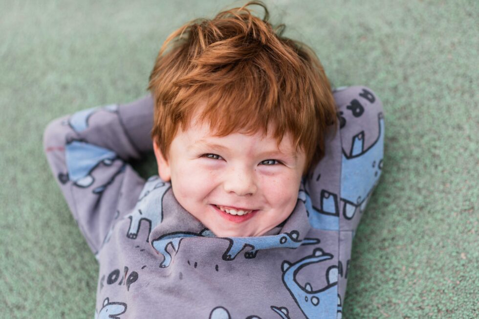 young pupil smiling at the camera whilst lysing down on the floor at nursery school in Skipton, North Yorkshire