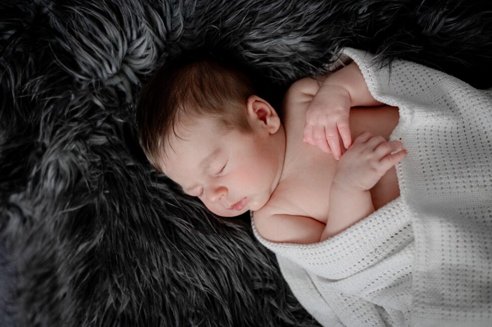 Newborn baby sleeping on a soft blanket during a cozy at-home newborn photography session in Harrogate, North Yorkshire