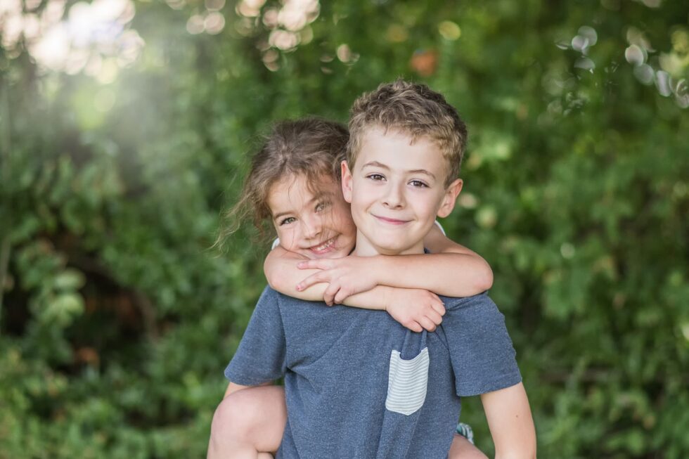 Siblings embracing in a park during a relaxed outdoor family photography session in Skipton, North Yorkshire