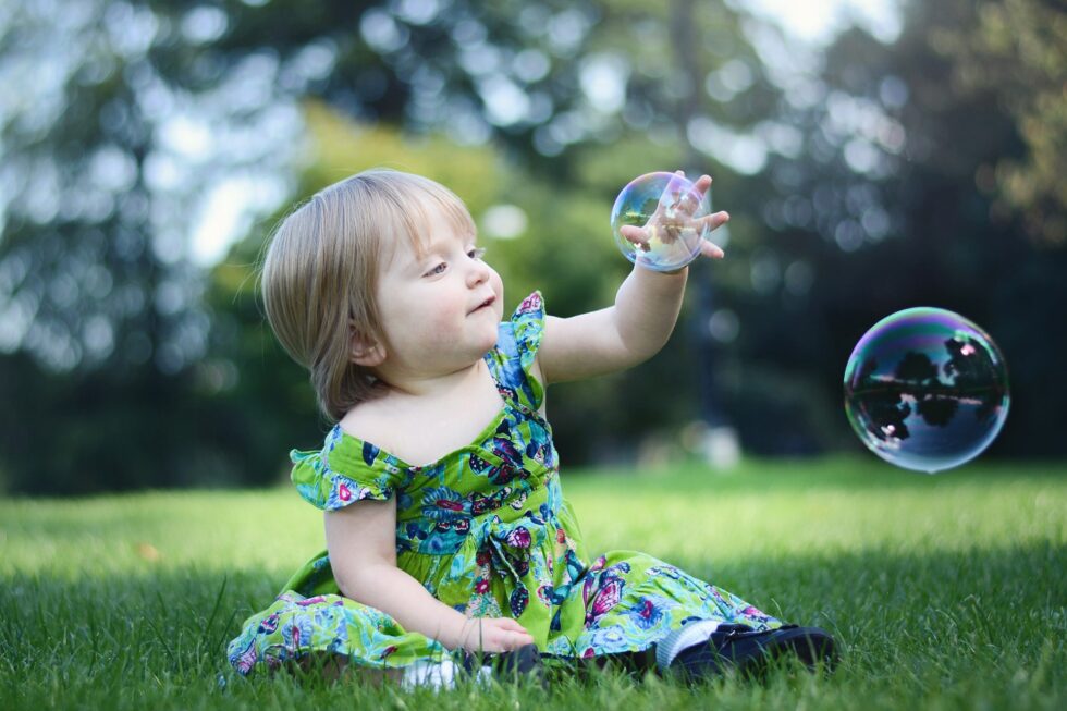 Little girl catching bubbles on the grass during an outdoor family photography session in Skipton, Yorkshire