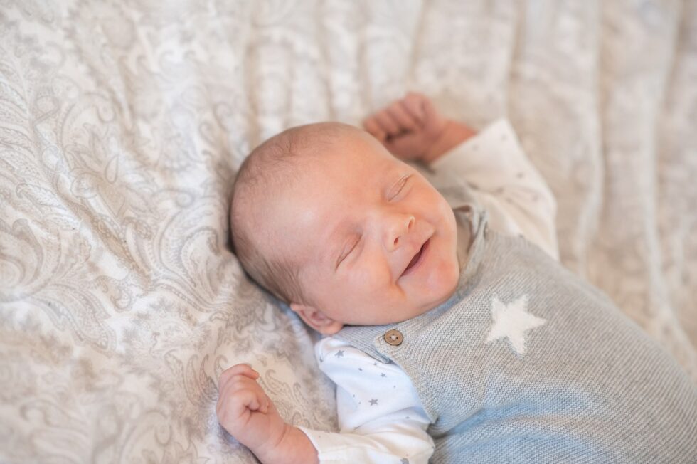 Smiling newborn baby wrapped in a star-themed blanket during an at-home newborn photo shoot in Skipton, North Yorkshire