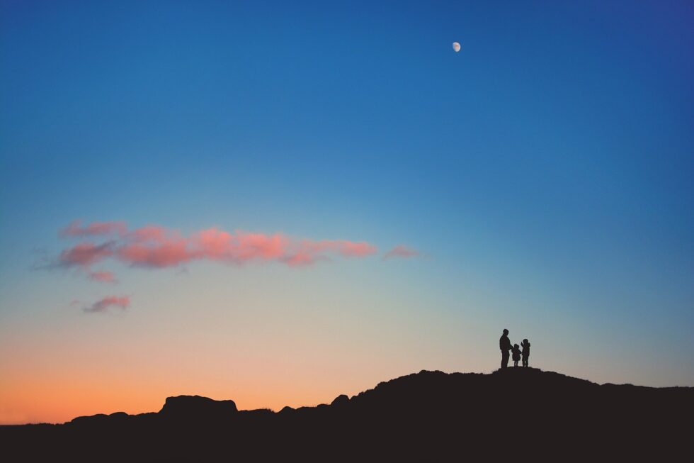 Family silhouetted against the sunset on a hill during an outdoor photography session on Ilkley Moor, Yorkshire