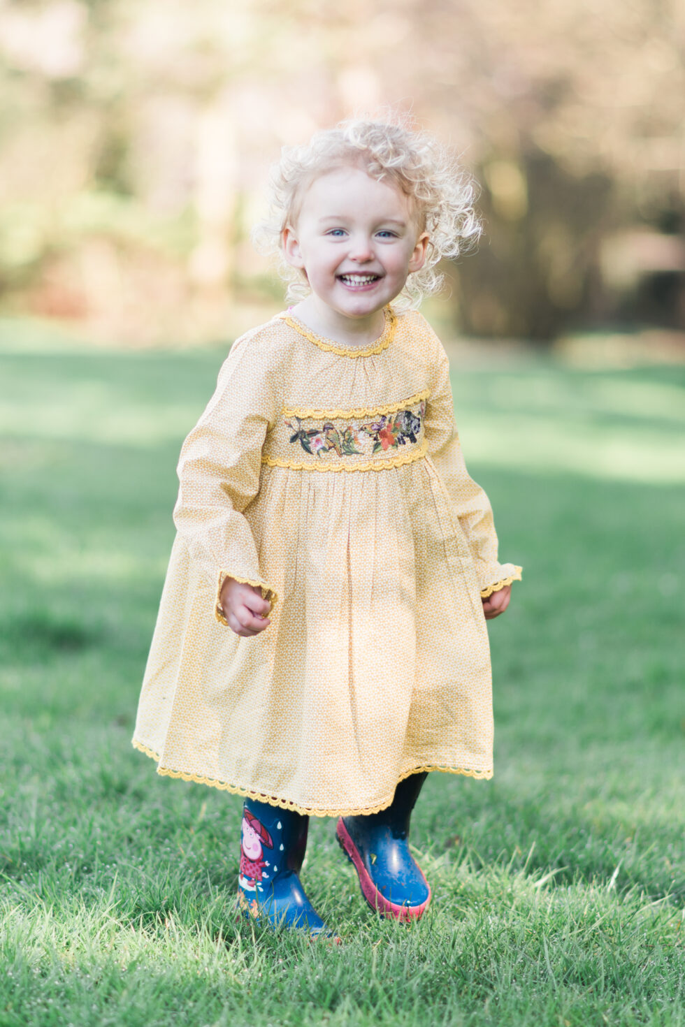 Laughing toddler in a yellow dress during a fun outdoor family photography session in Harrogate, North Yorkshire